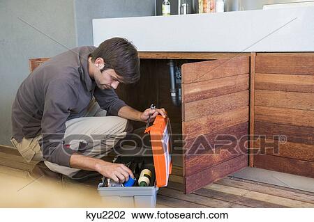 Stock Image - Man repairing a kitchen sink. Fotosearch