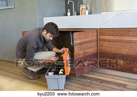 Stock Image - Man repairing a kitchen sink. Fotosearch