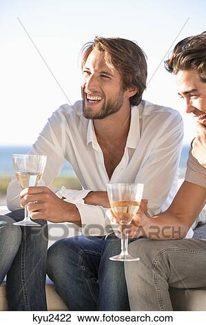 Stock Image - Man sitting with friends enjoying wine. Fotosearch