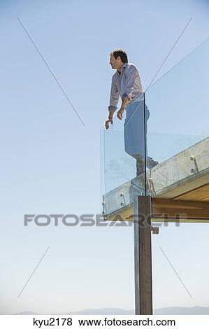Stock Photo - Man standing on the terrace looking away. Fotosearch