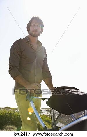 Man standing with a baby stroller View Large Photo Image Stock Photo - Man standing with a baby stroller. Fotosearch