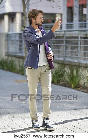 Man taking a picture with mobile phone on a street View Large Photo Image Stock Photo - Man taking a picture with mobile phone on a street. Fotosearch