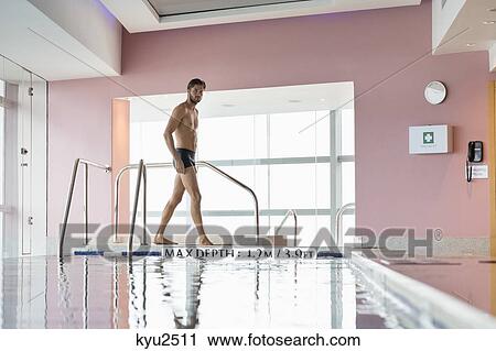 Stock Image - Man walking at the poolside. Fotosearch