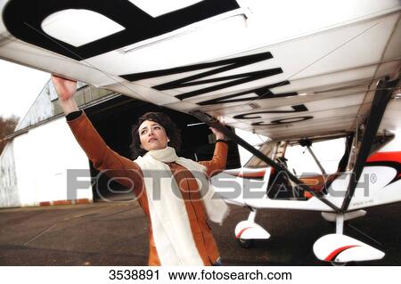 Stock Image - Pilot young woman checking the wing of her microlight.. Fotosearch