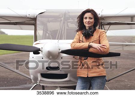 Stock Photograph - Pilot young woman standing in front of her microlight.. Fotosearch