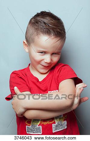 Stock Image - Portrait of a boy with arms crossed, mischievous look. Fotosearch