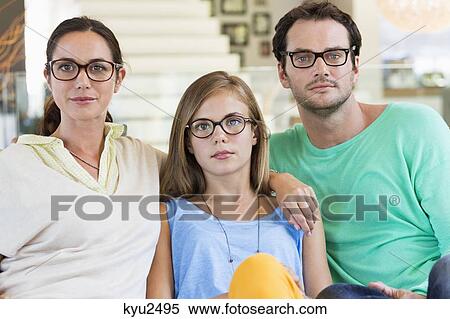Stock Photography - Portrait of a family sitting on a couch and wearing eyeglasses. Fotosearch