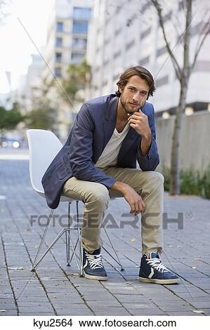 Portrait of a man sitting on a chair on a street View Large Photo Image Picture - Portrait of a man sitting on a chair on a street. Fotosearch