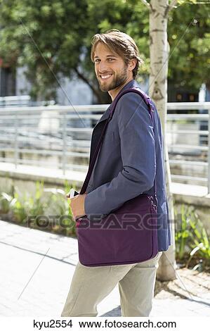 Picture - Portrait of a man walking on a street and smiling. Fotosearch