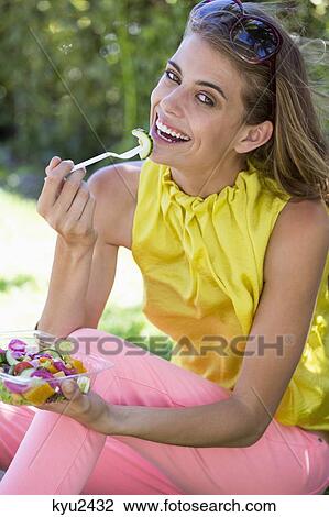 Stock Image - Portrait of a smiling woman eating salad. Fotosearch