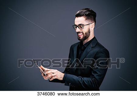 Stock Image - Portrait of a smiling young businessman holding a touch pad in his hands. Fotosearch