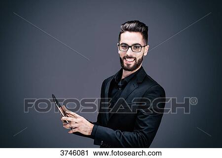 Portrait of a smiling young businessman holding a touch pad in his hands View Large Photo Image Stock Image - Portrait of a smiling young businessman holding a touch pad in his hands. Fotosearch
