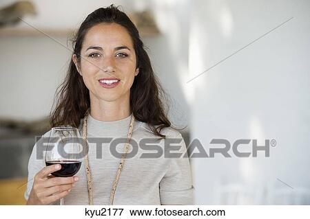 Stock Photo - Portrait of a woman holding a wine glass and smiling. Fotosearch