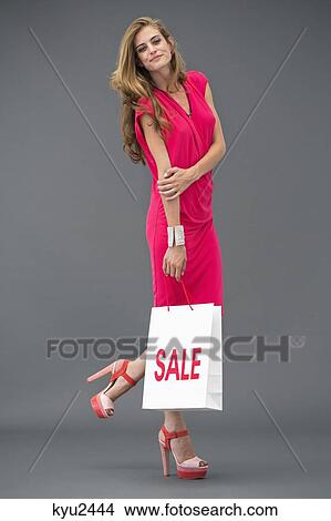 Portrait of a woman posing with a shopping bag View Large Photo Image Picture - Portrait of a woman posing with a shopping bag. Fotosearch