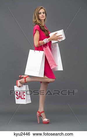 Portrait of a woman posing with shopping bags View Large Photo Image Stock Photograph - Portrait of a woman posing with shopping bags. Fotosearch