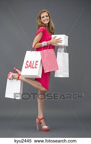 Portrait of a woman posing with shopping bags and smiling View Large Photo Image Stock Photography - Portrait of a woman posing with shopping bags and smiling. Fotosearch