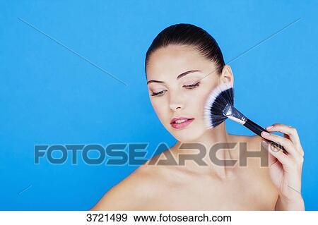 Portrait of a woman using make-up brush on face View Large Photo Image Stock Photo - Portrait of a woman using make-up brush on face. Fotosearch