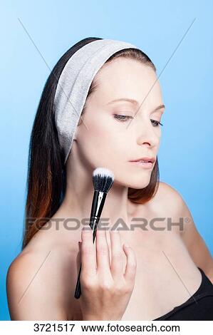 Portrait of a woman using make-up brush on face View Large Photo Image Stock Photo - Portrait of a woman using make-up brush on face. Fotosearch