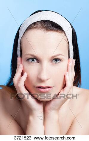 Stock Image - Portrait of a woman with hands on cheeks. Fotosearch