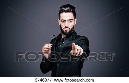 Portrait of a young businessman, a pair of glasses in one hand, pointing the lens View Large Photo Image Stock Photo - Portrait of a young businessman, a pair of glasses in one hand, pointing the lens. Fotosearch