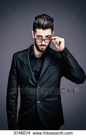 Portrait of a young businessman holding a pair of glasses, look toward the lens View Large Photo Image Picture - Portrait of a young businessman holding a pair of glasses, look toward the lens. Fotosearch