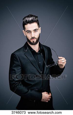 Portrait of a young businessman holding a pair of glasses, look toward the lens View Large Photo Image Stock Image - Portrait of a young businessman holding a pair of glasses, look toward the lens. Fotosearch