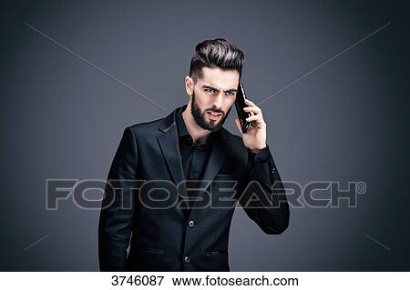 Stock Photo - Portrait of a young businessman upset during a telephone conversation. Fotosearch