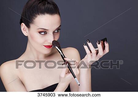 Portrait of a young woman applying makeup on her nose View Large Photo Image Stock Image - Portrait of a young woman applying makeup on her nose. Fotosearch