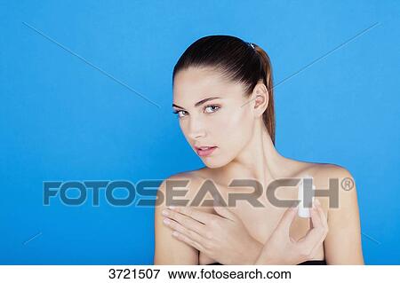 Portrait of a young woman applying lotion on her skin View Large Photo Image Stock Photo - Portrait of a young woman applying lotion on her skin. Fotosearch