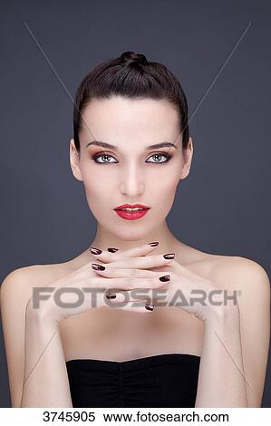 Portrait of a young woman hands under chin, looking toward the lens View Large Photo Image Stock Photography - Portrait of a young woman hands under chin, looking toward the lens. Fotosearch