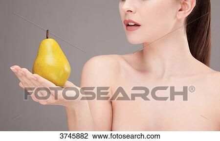 Stock Image - Portrait of a young woman holding a pear in his hand. Fotosearch