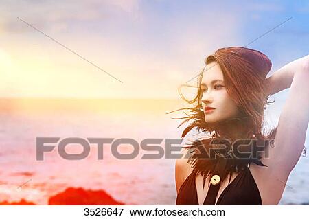 Portrait of a young woman holding hair by the sea View Large Photo Image Stock Photo - Portrait of a young woman holding hair by the sea. Fotosearch