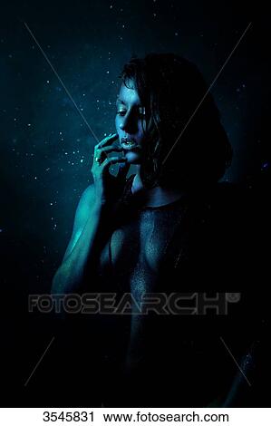 Stock Image - Portrait of a young woman painted in blue, daydreaming. Fotosearch