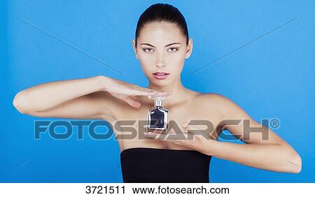 Portrait of a young woman with a bottle of perfume, look toward the lens View Large Photo Image Stock Image - Portrait of a young woman with a bottle of perfume, look toward the lens. Fotosearch