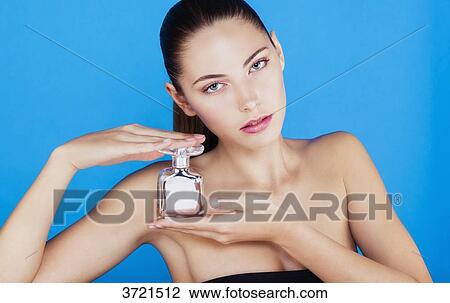 Portrait of a young woman with a bottle of perfume, look toward the lens View Large Photo Image Stock Image - Portrait of a young woman with a bottle of perfume, look toward the lens. Fotosearch