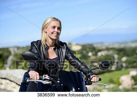 Stock Photo - Portrait of attractive young blonde woman riding motorbike in summer.. Fotosearch