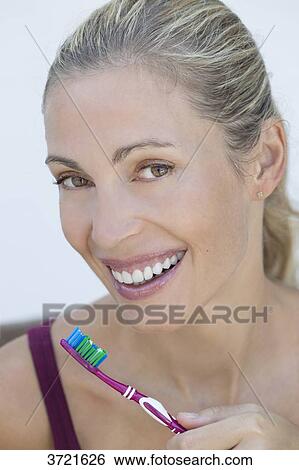 Stock Photograph - Portrait of smiling blond woman with toothbrush. Fotosearch
