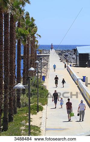 Picture - Portugal, Algarve, Portimao. People walking on the embankment.. Fotosearch