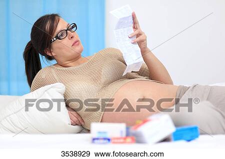 Stock Photo - Pregnant woman reading drug label. Fotosearch