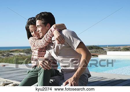 Picture - Romantic couple sitting on a boardwalk on the beach. Fotosearch