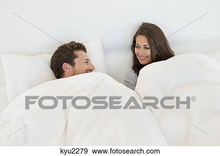 Stock Photo - Smiling couple resting on the bed. Fotosearch