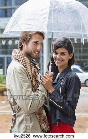 Stock Photograph - Smiling couple under an umbrella. Fotosearch
