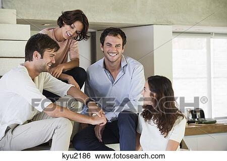 Stock Photograph - Smiling friends sitting on steps. Fotosearch