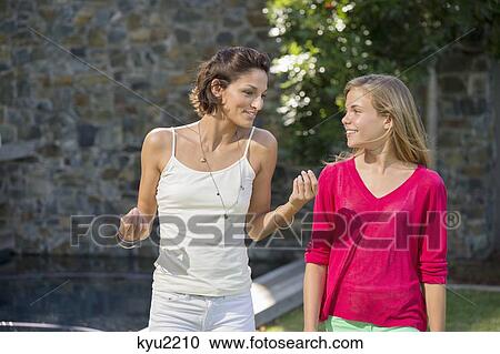 Stock Image - Smiling mother and daughter talking to each other. Fotosearch