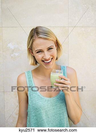 Stock Image - Smiling woman drinking detox. Fotosearch