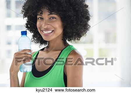 Smiling woman drinking water from a bottle View Large Photo Image Picture - Smiling woman drinking water from a bottle. Fotosearch