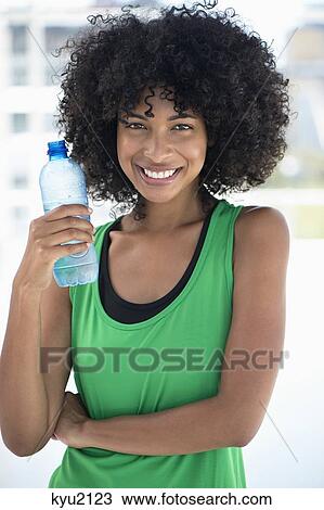 Stock Image - Smiling woman drinking water from a bottle. Fotosearch
