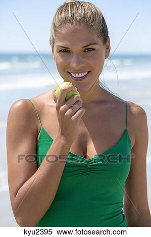 Smiling woman eating a green apple View Large Photo Image Stock Photography - Smiling woman eating a green apple. Fotosearch