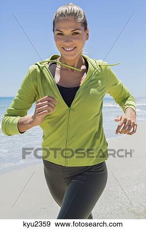 Stock Photo - Smiling woman running on the beach. Fotosearch
