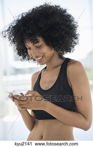 Stock Image - Smiling woman text messaging on a mobile phone. Fotosearch